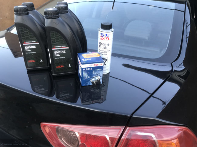 Пять литровых канистр с моторным маслом на багажнике седана Митсубиси Лансер 10